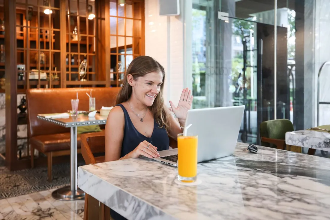 A new agency owner smiling at her laptop in a cafe